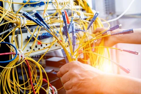 Network engineer working in server room. Connecting network cables to switches Stock Photos