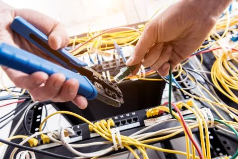 Network engineer working in server room. Connecting network cables to switches Stock Photos