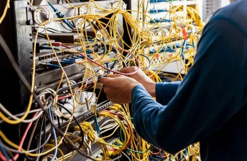Network engineer working in server room. Connecting network cables to switches Stock Photos