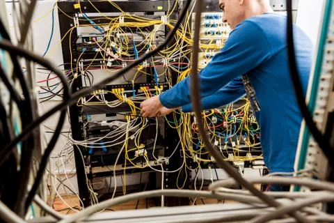 Network engineer working in server room. Connecting network cables to switches Stock Photos