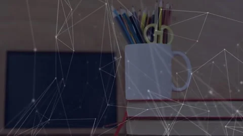 Network mesh drifting and weaving around stack with mug of pencils and scissors Stock Footage 320128611