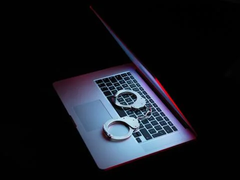 Network security, set of handcuffs sitting on laptop computer Stock Photos