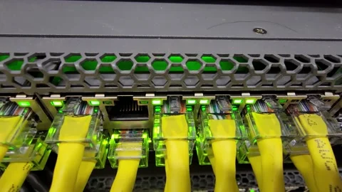 Network switch with yellow ethernet cables and flashing lights indicating Stock Footage 187512464