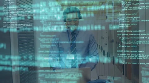 Network tech answering phone, typing on laptop amid server racks, code overlay Stock Footage 332685863