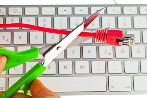Netzwerkkabel wird mit einer Schere ueber einer Computertastatur durchgesc... Foto stock