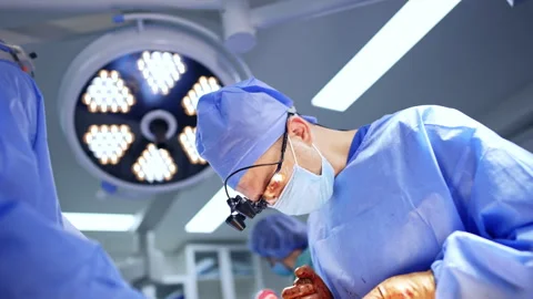 Neurosurgeon bent over the patient while performing operation. Low angle view. Stock Footage 334877018