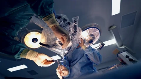Neurosurgery through the microscope. Doctors in medical uniform perform  Stock Footage 118215247