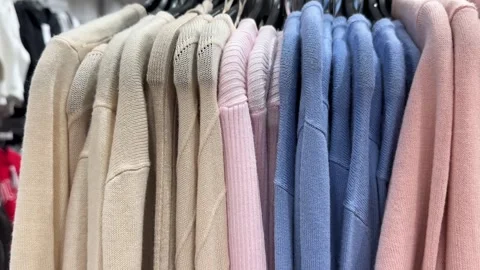 Neutral and Pastel Sweaters Hanging in Contemporary Clothing Store Stock Footage 336320156