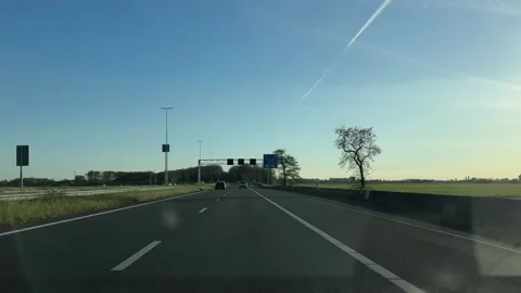 Neutral driver's perspective of highway road with signs and trees under blue 스톡 동영상 342752651