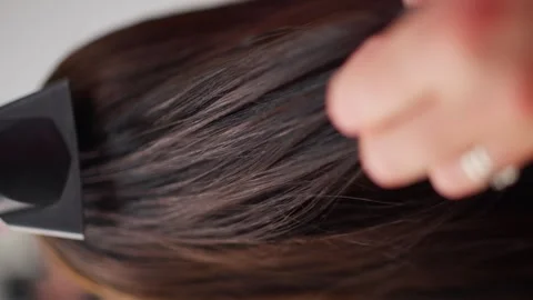 Neutral focused styling and smoothing hair with a brush and flat iron Vidéo 346760728