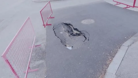Neutral roadside pothole with red triangular warning sign observed on concrete Stock Footage 345203019