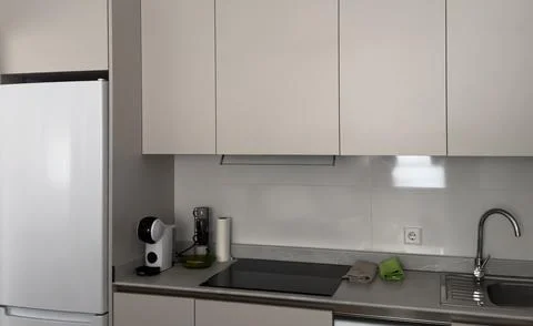 Neutral side view of a modern kitchen with ceramic tiles, plastic and metal.. Stock Photos