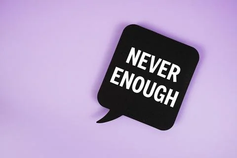 Never Enough text with speech bubble top view on purple background Stock Photos