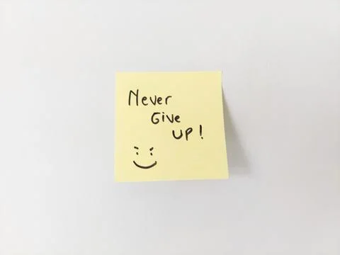Never Give Up Message and Smiling Doodle on a Sticky Note for Motivation Stock Photos