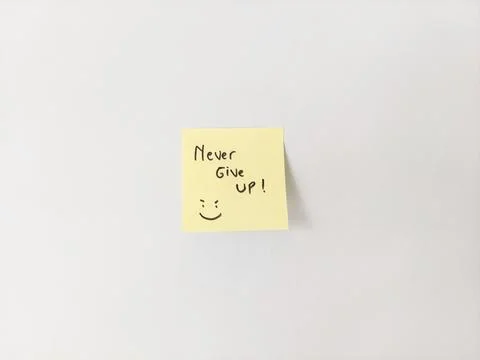 Never Give Up Message and Smiling Doodle on a Sticky Note for Motivation Stock Photos