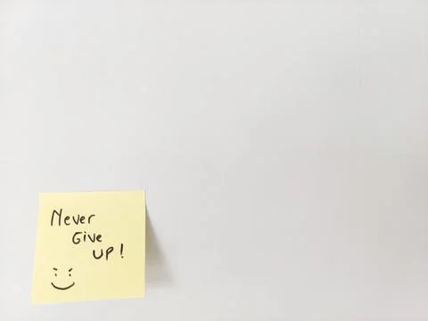 Never Give Up Message and Smiling Doodle on a Sticky Note for Motivation Stock Photos