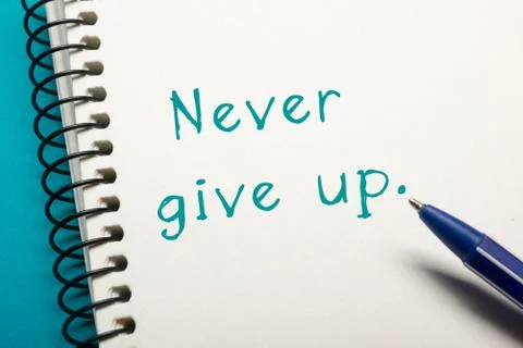Never give up message - Office table top view. Notepad with text and pen Photos