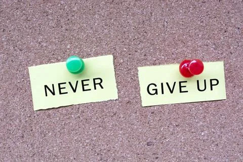Never give up text on stick note and pinned to a cork notice board. Stock Photos