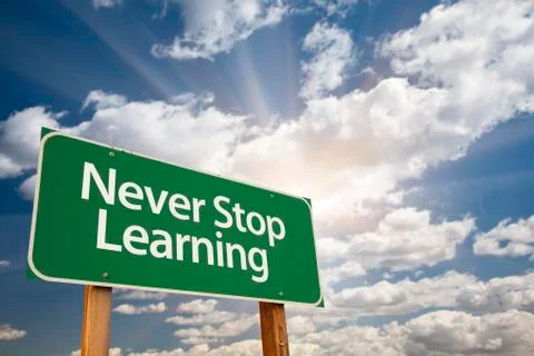 Never Stop Learning Green Road Sign with Dramatic Clouds and Sky. Stock Photos