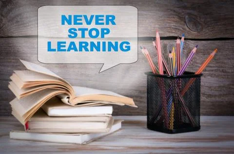 Never Stop Learning. Stack of books and pencils on the wooden table. Stock Photos