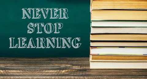 Never stop learning is written on a chalkboard with stacks of books behind it Stock Photos
