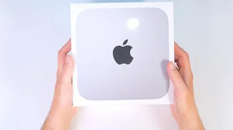 New Apple Mac Mini inside a box lying on a white table, top view. Close up of Stock Photos
