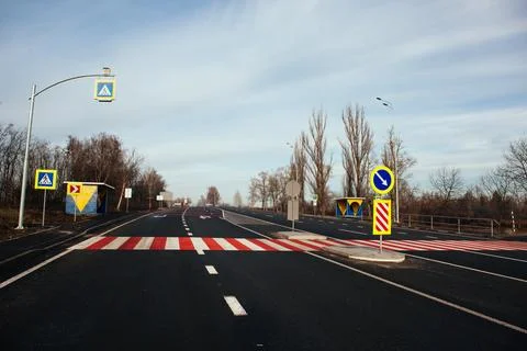 New asphalt road with markings and road signs in the sun's rays Stock Photos