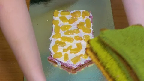 A new biscuit cake is placed on the cream layer of the cake Stock-Footage 123577019