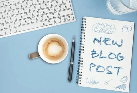 NEW BLOG POST scribbled on spiral notepad on blue desk with computer keyboard, Stock Photos