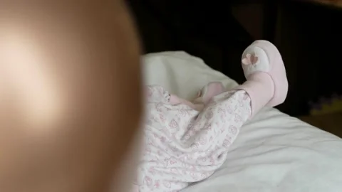 New born tiny feet on pastel blanket with festive ballon on foreground. Close up Stock Footage 165779228