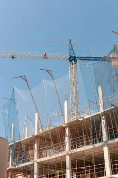 New building construction process. Safety nets, structural beams highlight Stock Photos