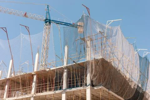 New building construction process. Safety nets and structural beams highlight Stock Photos