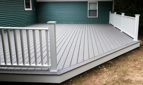 New composite deck on the back of a house with green vinyl siding. Stock Photos