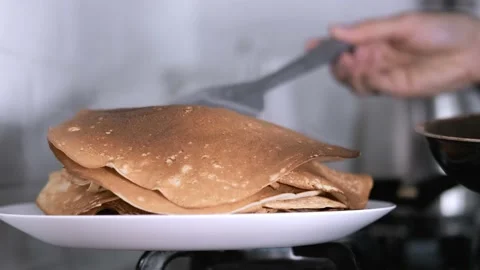 New crepe in stack of fresh baked crepes with raised steam from pan, cooking Stock-Footage 229553252