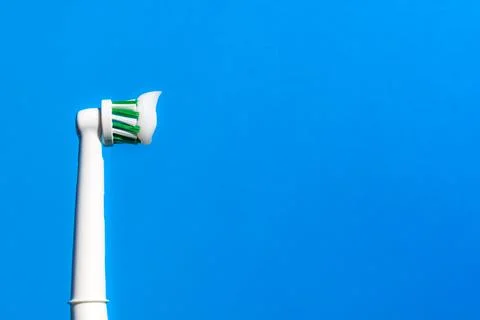 New electric toothbrush with toothpaste on a from the side blue background. Stock Photos