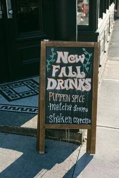 New fall drinks announced on a chalkboard sign outside a cozy cafe in autumn Stock Photos