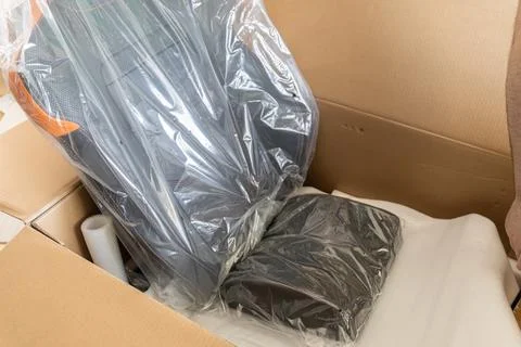 A new gaming chair inside an opened cardboard box wrapped in plastic, Stock Photos