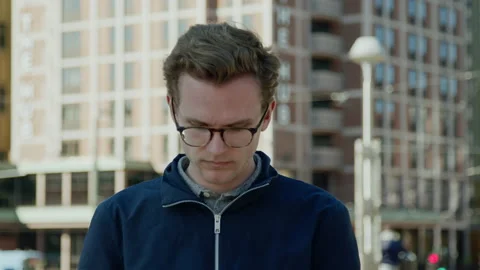 New generation caucasian looking down on his phone middle of downtown Stock Footage 135418925