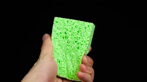 New green sponge in hand of man in front of black background Stock Footage 117447645