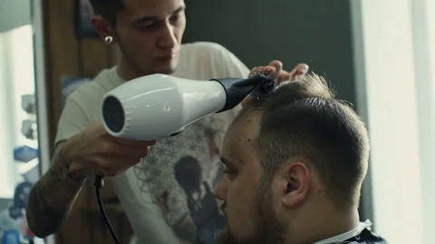 New hairstyle. Side view of young bearded man getting groomed at hairdresser Stock Footage 69765204