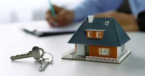 New house scale model and keys on the table at real estate agent office. doll Stock Footage 107987311