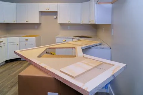 New kitchen layout featuring white cabinets marble countertop being installed in Stock Photos