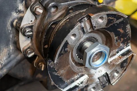 New lock nut sits on heavy machine shaft output flange during workshop main.. Stock Photos