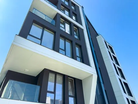 New modern building with large windows in urban area under clear blue sky Stock Photos