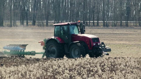 A new, modern tractor plows heavy soil with a reverse plow, storks collect food Stock Footage 130970265