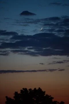 New moon in the evening sky with clouds Stock Photos