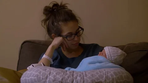 New mother stares at infant son in arms Stock Footage