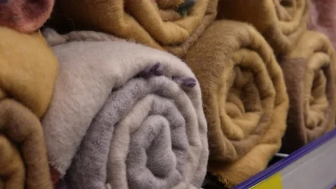 New multi-colored woolen plaids, twisted into rolls, on the store shelf Stock Footage 232983059