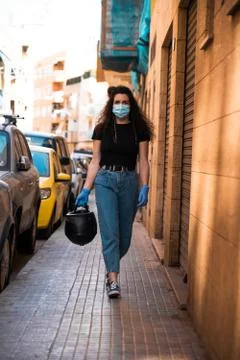The new normal in 2020 after isolation: a young woman walks on the sidewalk o Stock Photos