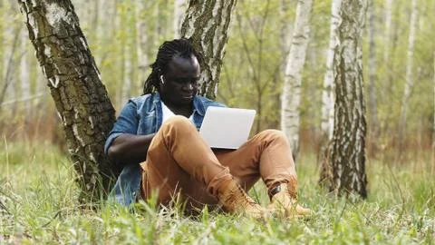 New normal. Remote work concept. African man using laptop in the nature Stock Photos